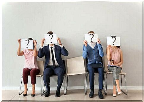 A group of people holding a question mark sign in front of their faces