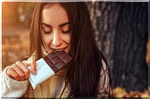 A woman enjoying a piece of chocolate in a sunny autumn weather